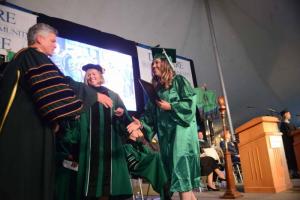Amber Willey from Rehoboth Beach holds her diploma for physical therapy assistant as she prepares to shake hands with Del Tech President Dr. Mark Brainard. Del Tech 2107