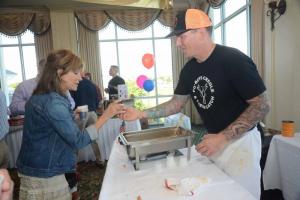 Chef Mike Clampitt of Po’Boys Creole and Fresh Catch serves Debbie Knight a sample of his jambalaya. Top Chef