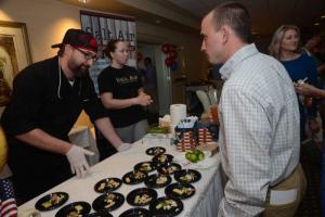 At the Salt Air Table Chef Gary Wilson, left, and Pastry Chef Rhiannon Lorah explain their Compressed Watermelon, Beer Brined Crispy Chicken Skin and Roasted Corn and Crab Salsa to Connor McDonald. Top Chef