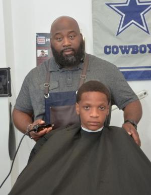 Pro Cutz owner Chester Hope Jr. prepares to clip Ryan Howell’s hair. Howell is attending Millsboro Middle School. Collena Hope, the owner’s wife, helped coordinate the event.