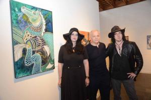 Lynnette Shelley stands next to her ink and acrylic image “Hippokanpos,” a mythological sea horse. Having a great love of wildlife, folktales, tribal art and world mythology, Shelley fuses these influences into her strikingly unique artworks. Shown standing with Shelley are RAL Creative Director Jay Pastore, center, and Brandon Lord Ross. RAL Raubacher