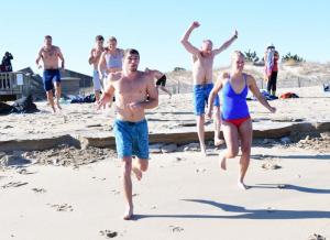 Trevor Ricker, center, leads his fiancée Lacey Mallman, right, and father Keith into the frigid Atlantic.