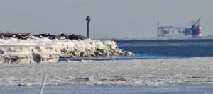 As ice forms along the rocks near Roosevelt Inlet in Lewes, a huge ship can be seen far off in the distance. RON MACARTHUR PHOTO