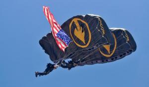 A member of the U.S. Special Operations Command Parachute Team brings in the U.S. Flag from 5,000 feet to start the air show.