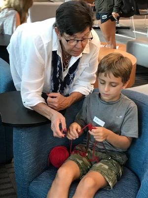 Experienced knitter Donna Conway, left, helps novice Aiden Wilkinson.