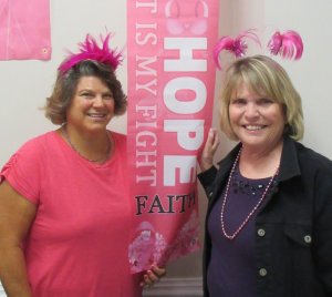 Mary Ruggiero, left, and Deb Kelley are shown with one of the many pink banners adorning the Elks hall for the breast cancer awareness dinner.