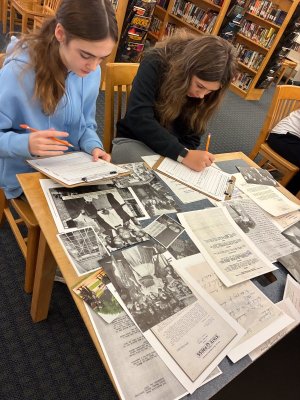 Students Lily Barrett-Kuntz, left, and Isabella Iarussi review old newspaper clippings related to Brown v. Board of Education.