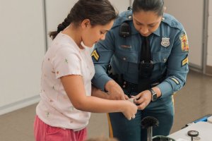 Detective Elizabeth Zambrano, H.O.B. school resource officer, right, helps Amina Cove create a fingerprint.