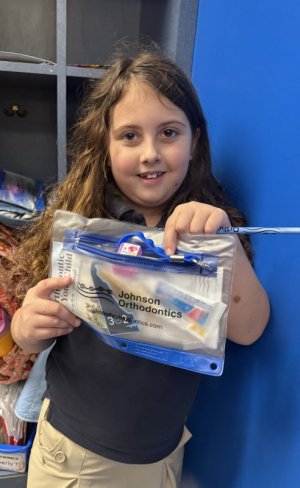 Elizabeth Donahue shows off a big pack of Johnson Orthodontics healthy habit information, stickers, pencils and more.