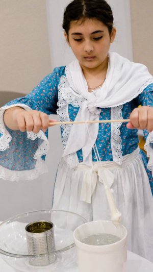 Legacy Academy sixth-grade student Sofia Gladding makes a candle out of beeswax.